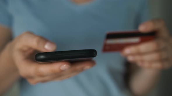 Closeup Woman's Hands Holding a Credit Card and Using Cell Phone for Online Shopping