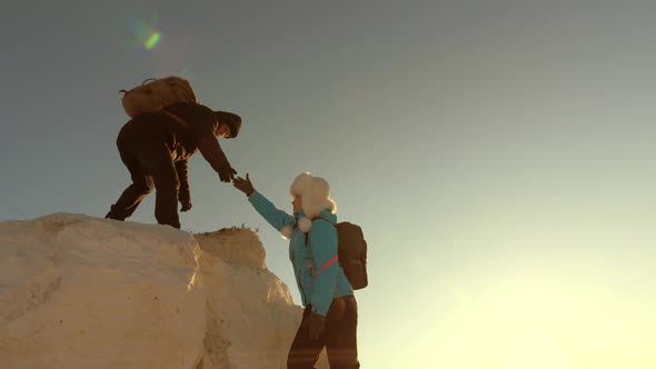Male Tourist Helps a Traveler Girl To Climb Mountain, Reaches Out Helping Hand. Free Woman Climber