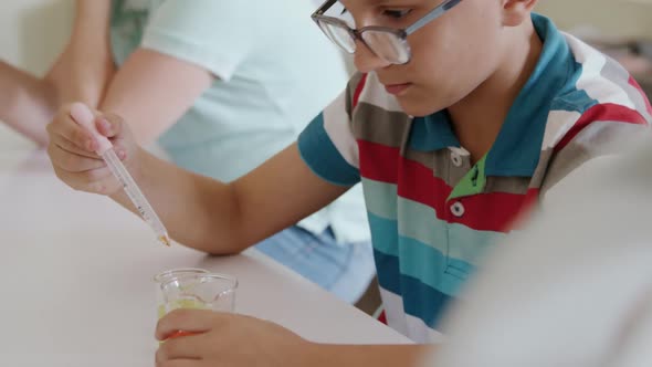 Girl wearing glasses using pipette and beaker