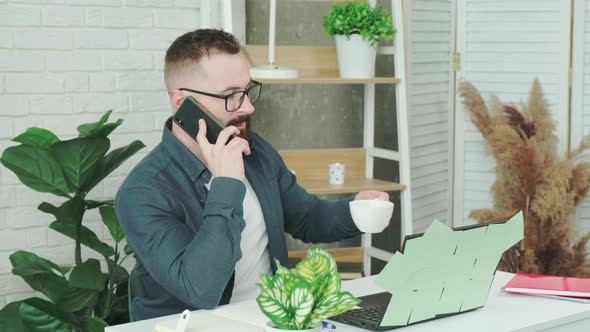 Handsome Bearded Man Drinking Coffee While Talking on a Smart Phone