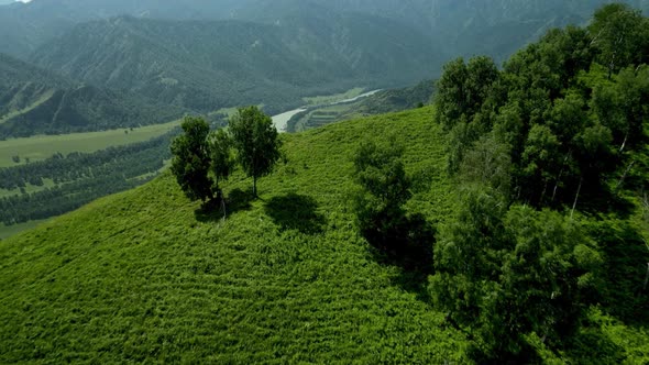 The Camera Flies Out From Behind the Hill to a Beautiful Valley with a River