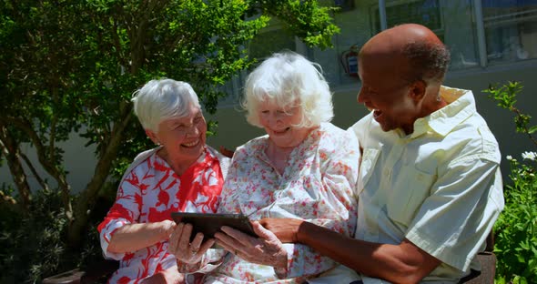 Group of active mixed-race senior friends using digital tablet in the garden of nursing home 4k