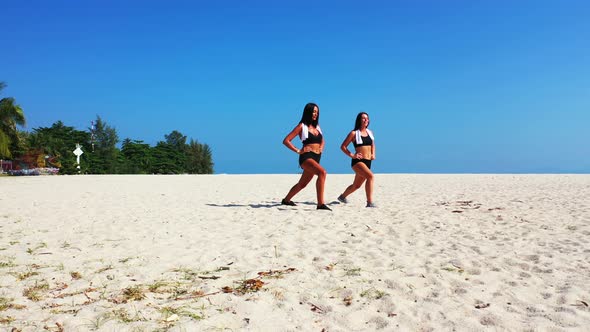 Pretty happy ladies on holiday enjoying life at the beach on summer white sandy and blue background 