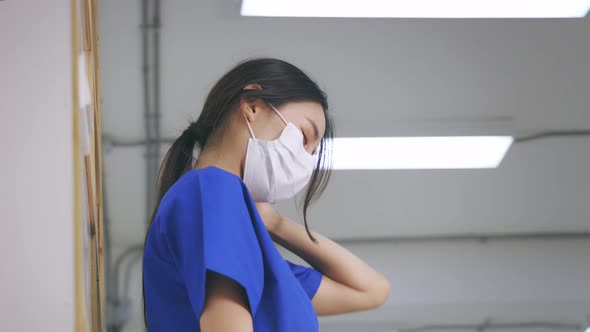 Tired Young Asian Female Doctor in Uniform and Mask Suffering From Neck Pain in Hospital