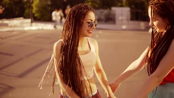 Two Happy Women with Dreads Walking on the Empty Road and Talking in Summer