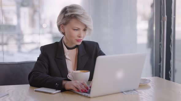 The Woman Works with a Laptop in a Cafe