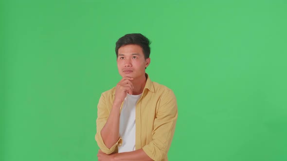 Young Asian Man Thinking About Something Then Raising Her Index Finger In Green Screen Studio