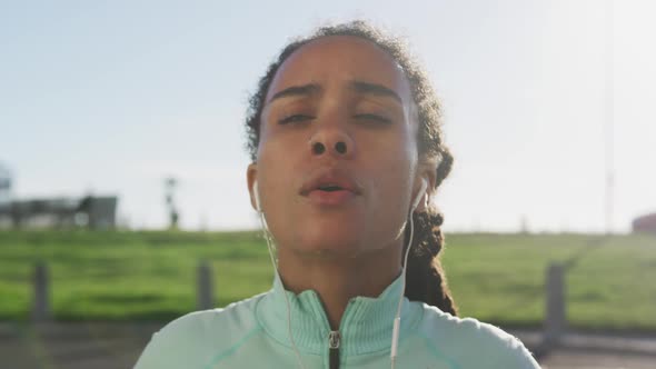 African american woman in sportswear wearing earphones on a sunny day