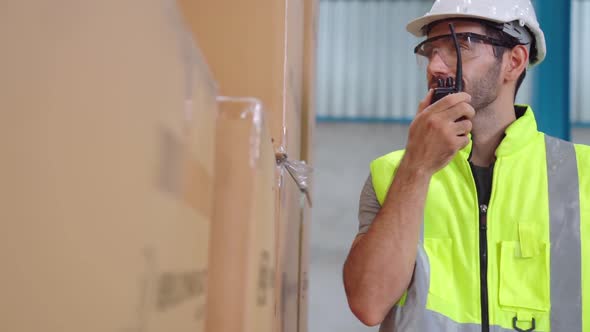 Professional Cargo Worker Talks on Portable Radio to Contact Another Worker