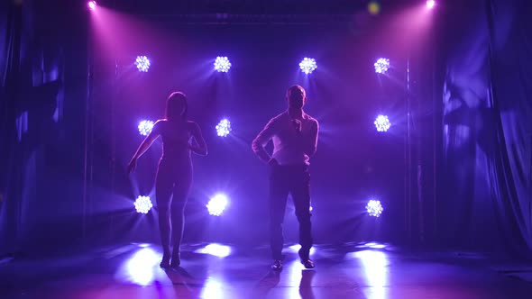 Young Couple Dancing Latin Music. Bachata, Merengue, Salsa. Shot in a Dark Studio with Neon Lights