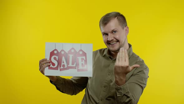 Great Discounts. Happy Cheerful Blonde Man in Blue Shirt Showing Sale Word Advertisement Inscription