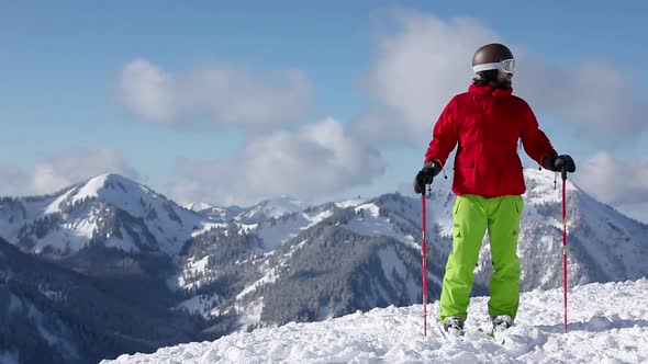 Skier taking in scenery and pointing to mountains with ski pole