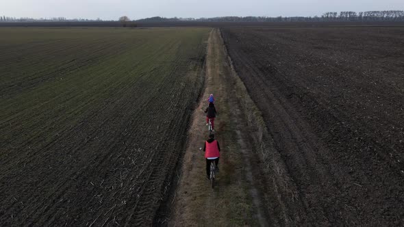 Aerial drone view from above of family ride on bikes outdoors on the spring field