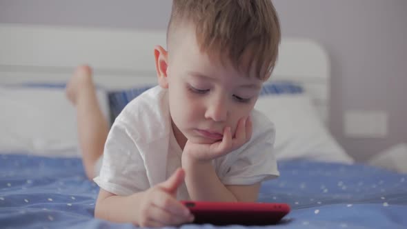 Cute Little Boy Preschool Child Using a Phone or Digital Tablet Technology Device Looks Telephone