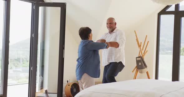 Happy senior diverse couple dancing in living room at retirement home