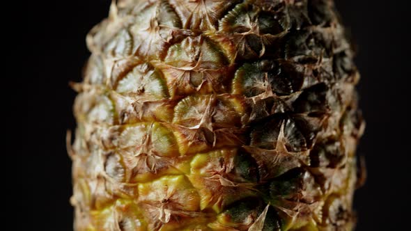Macro shot of rotating pineapple fruit isolated on black background