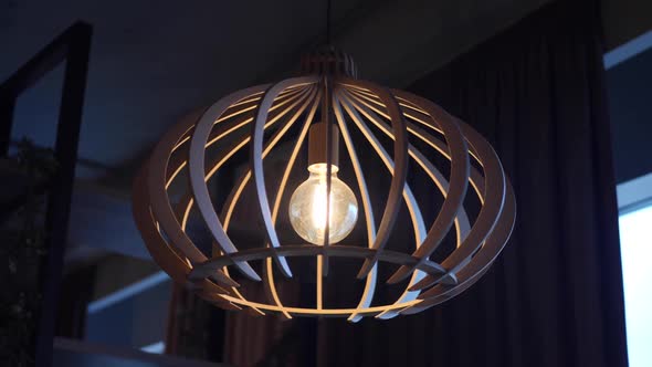 Wooden Chandelier with a Light Bulb Hangs in the Evening in Cafe