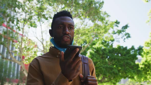 African american businessman with face mask talking on smartphone