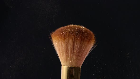 Shimmer Powder Coming Down on Makeup Brush on Black Background