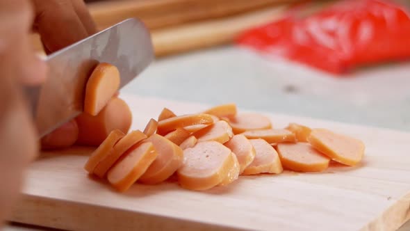 Close up of a knife cuts the sausage into small pieces.