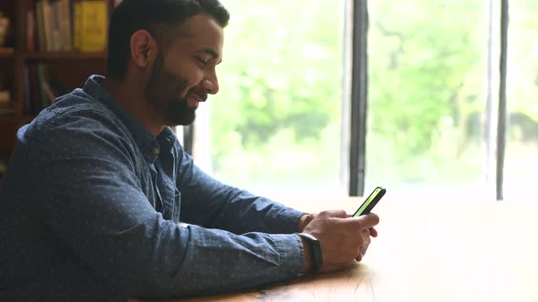 Young Handsome Indian Freelancer Man Using Smartphone for Online Chatting