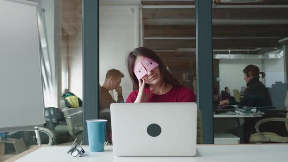 Inefficient Tired Female Employee Pretends Working Sleeping with Stickers on Face Sits at Desk