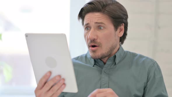 Middle Aged Man Reacting to Loss on Tablet