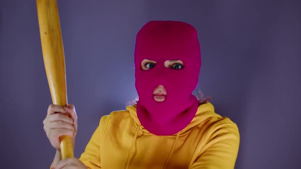 Young Woman in Pink Balaclava with Baseball Bat in Hands