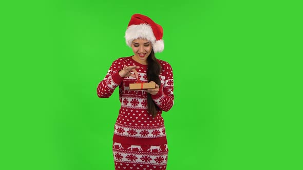 Sweety Girl in Santa Claus Hat Is Opening the Gift and Rejoicing. Green Screen