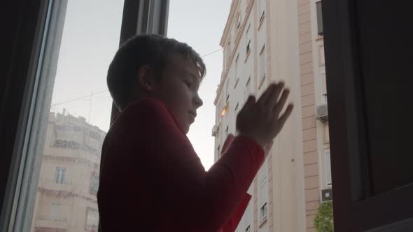 Child in coronavirus lockdown applauding to health workers from open window