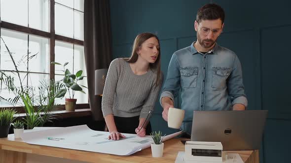 Young Woman and Man As an Architects Working with Blueprints, Laptop and House Models in the Office