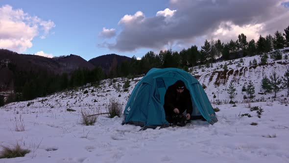 Hiker, arriving at tent, in the winter mountains