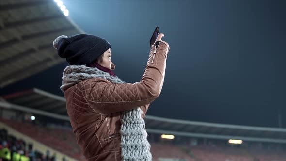 Girl Dressed in Hat and Scarf Shooting Video at the Stadium