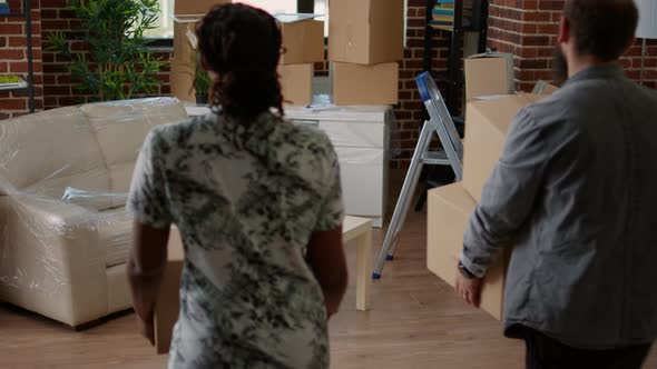 Married Couple Stacking Moving Carton Boxes in Purchased Real Estate