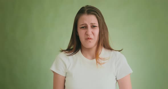 Disgusted Woman Makes Grimaces Posing for Camera on Green