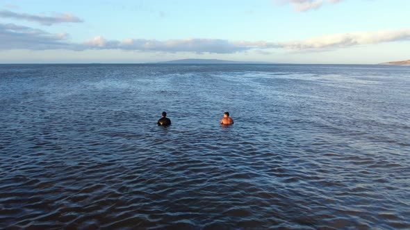 two male surfers sitting on their boards and waiting for the waves