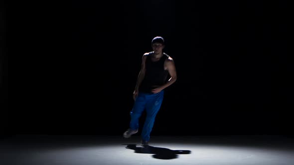 Young Dancer Man in Cap Dancing Breakdance on Black