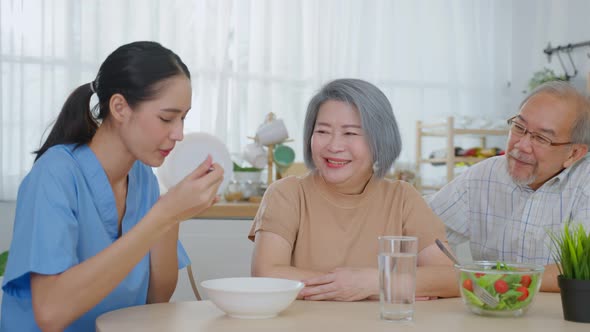 Asian senior elderly couple eating easy digestible food and salad together in kitchen at home.