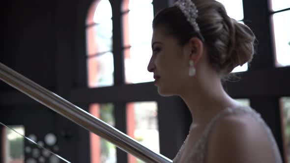 Smiling bride in trained wedding dress climbing stairs in hotel