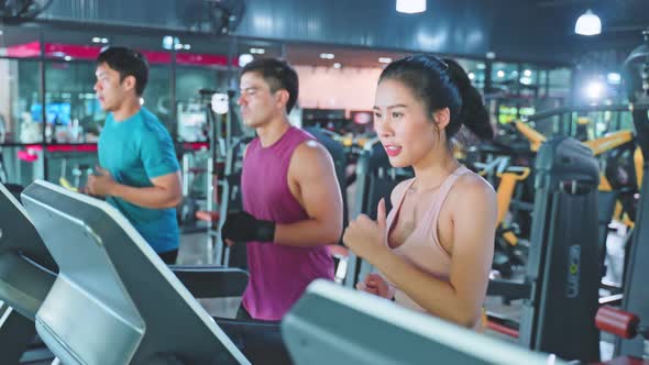 Group of Asian young athlete sport man and woman exercise by running in Treadmill in fitness gym.