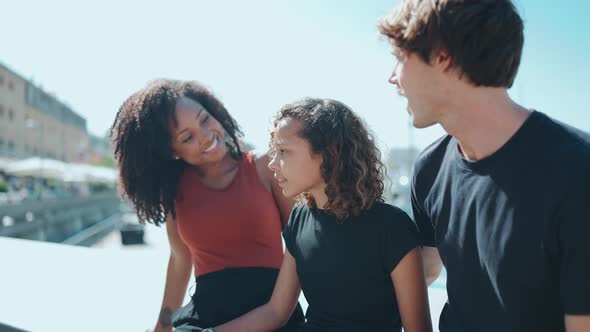 Positive multiethnic family talking on the embankment