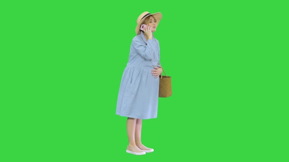 Worried Pregnant Woman Talking on the Phone Having Contractions on a Green Screen, Chroma Key