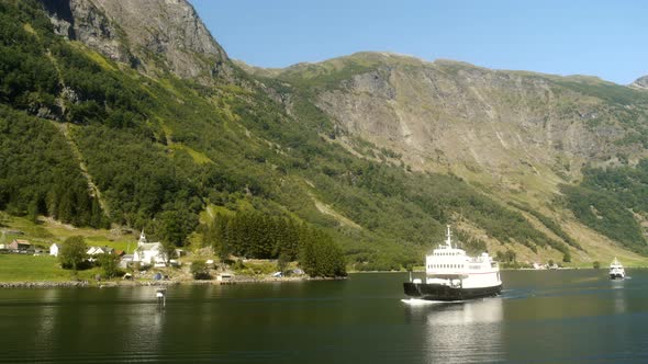 Ship Sailing Past Small Village In Norway Fjords