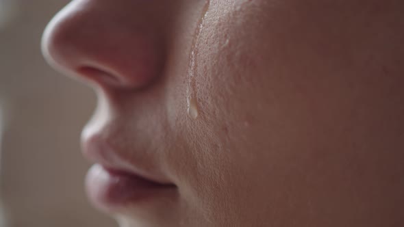 Close-up of a Woman's Cheek with a Tear Sliding Down It. A Tear Slowly Descends on the Distressed