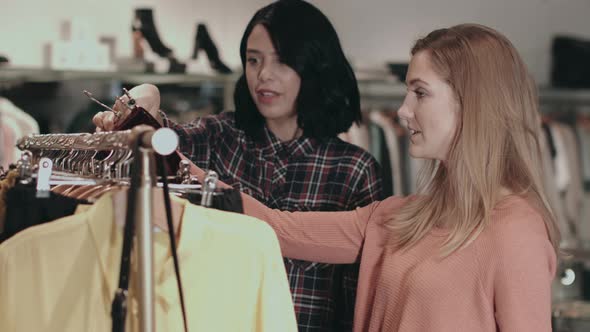 Young adult women looking at clothes in shop