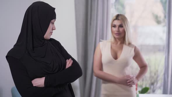 Conservative Muslim Woman Looking Back at Modern Caucasian Girl in Candid Dress and Turning Away