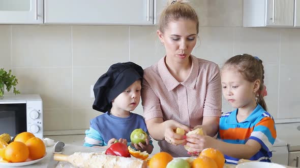 Mother Cook Food in Kitchen Together with His Son and Daughter. Little Chefs at Work