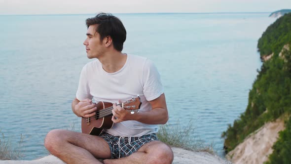 Young Chill Man Playing Ukulele and Singing  Sitting on the Mountain