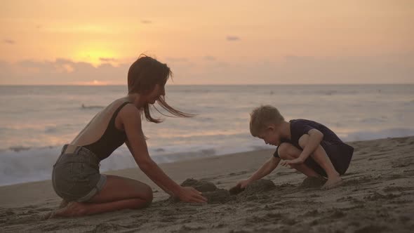 Mom and Son Building Sand Castle on Beach