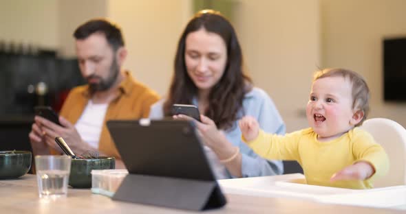 Baby and Parents Busy in a Digital Gadgets During a Lunch at Home